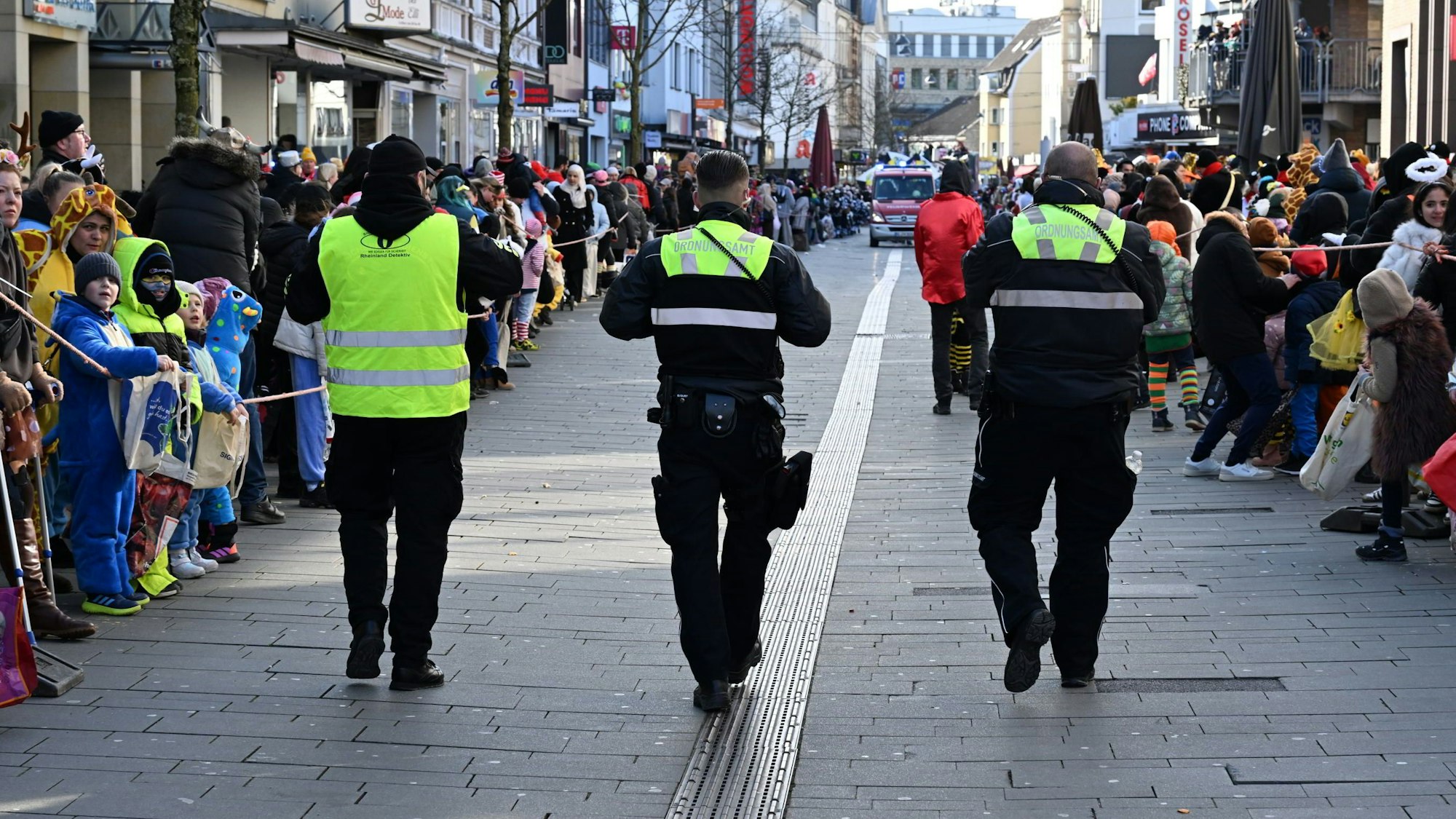 Zwei Mitarbeitende des städtischen Ordnungsamtes gehen mit einem Security-Mitarbeiter den Gladbacher Zochweg entlang.