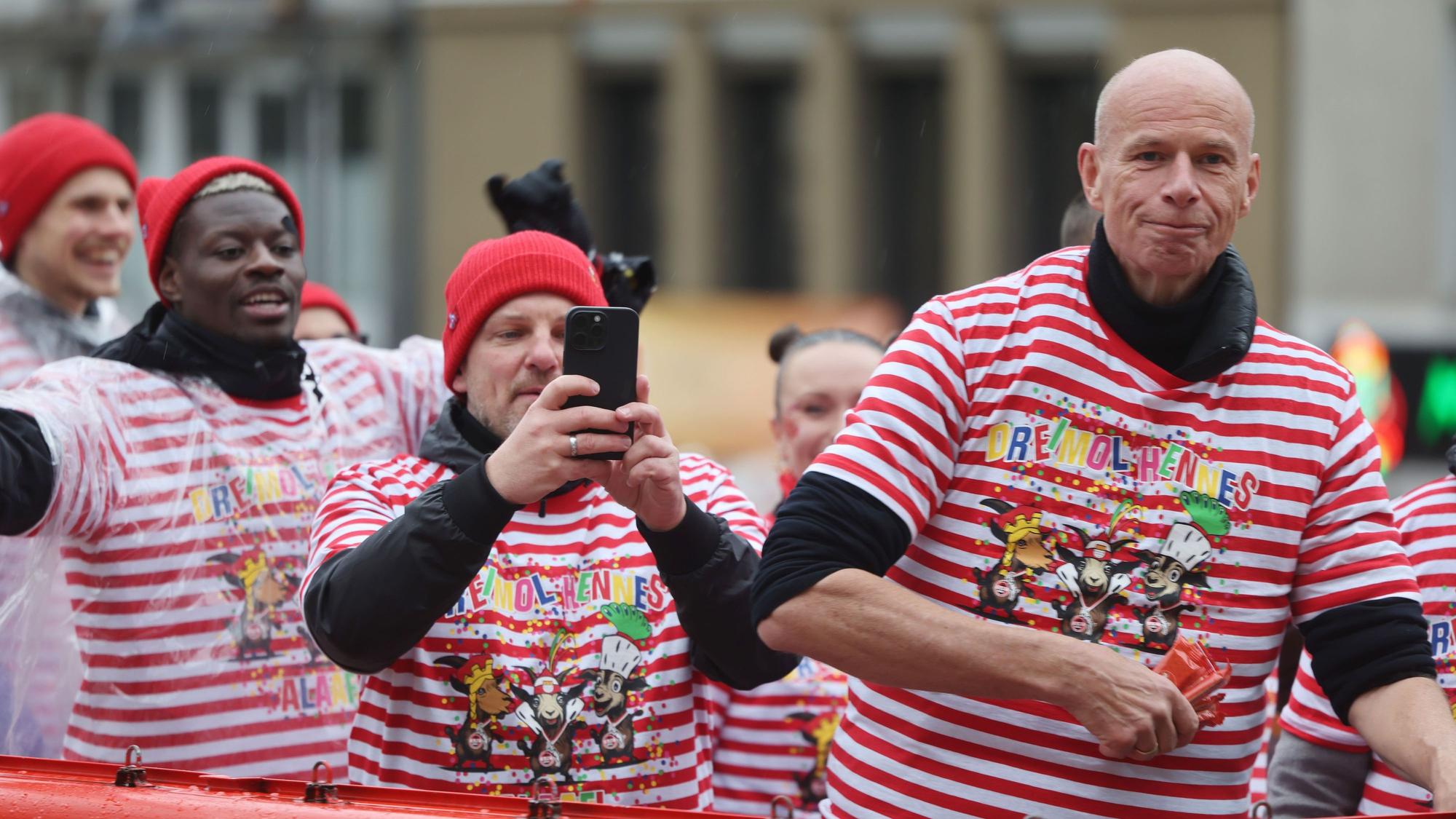 Ragnar Ache (l.), Spieler des 1. FC Köln, Trainer Lukas Kwasniok und Jörn Stobbe, Präsident des 1. FC Köln, nehmen am Rosenmontagszug in Köln teil.