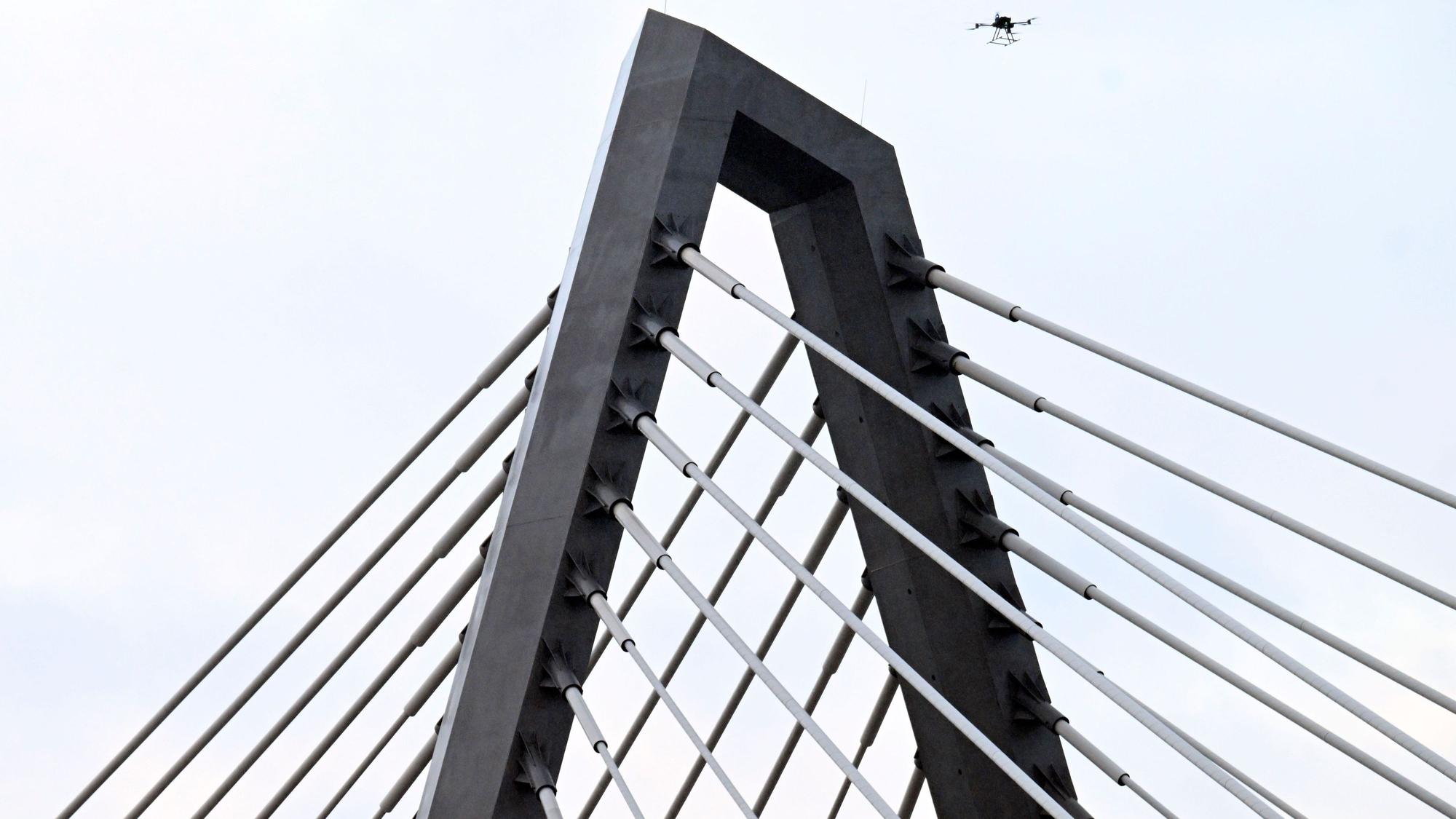 16.02.2026, Nordrhein-Westfalen, Leverkusen: Eine Drohne steigt neben den Drahtseilen der Leverkusener Rheinbrücke auf, um den Zustand der Konstruktion zu überprüfen. Die Autobahnmeisterei sperrte die Autobahn 1 (A1) in beide Richtungen, nachdem sich über Nacht Eis gebildet hatte, das auf darunter fahrende Fahrzeuge hätte stürzen können. Foto: Roberto Pfeil/dpa +++ dpa-Bildfunk +++