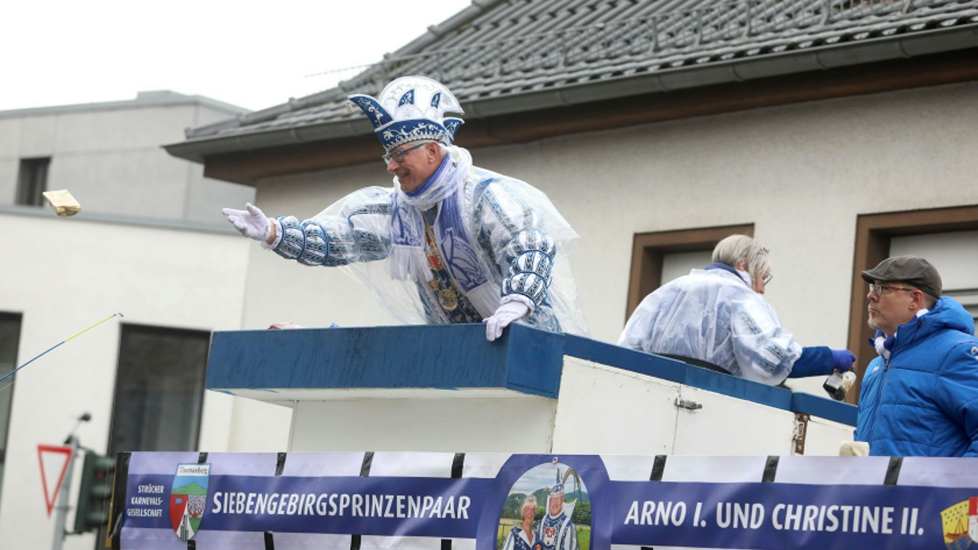 Ein Prinzenpaar in Blau-Weiß wirft Kamelle vom Wagen.