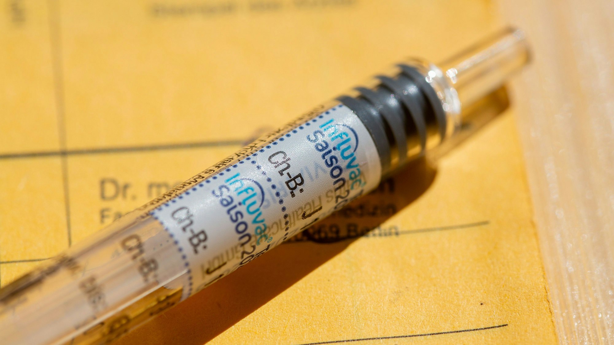 ILLUSTRATION - 03.04.2025, Berlin: Eine Spritze mit dem Impfstoffetikett «Influvac» liegt auf einem gelben Impfpass mit ärztlichen Eintragungen. (zu dpa: «Grippeimpfung nicht verfügbar? Hausärzte gegen Bestellregeln») Foto: Fernando Gutierrez-Juarez/dpa +++ dpa-Bildfunk +++