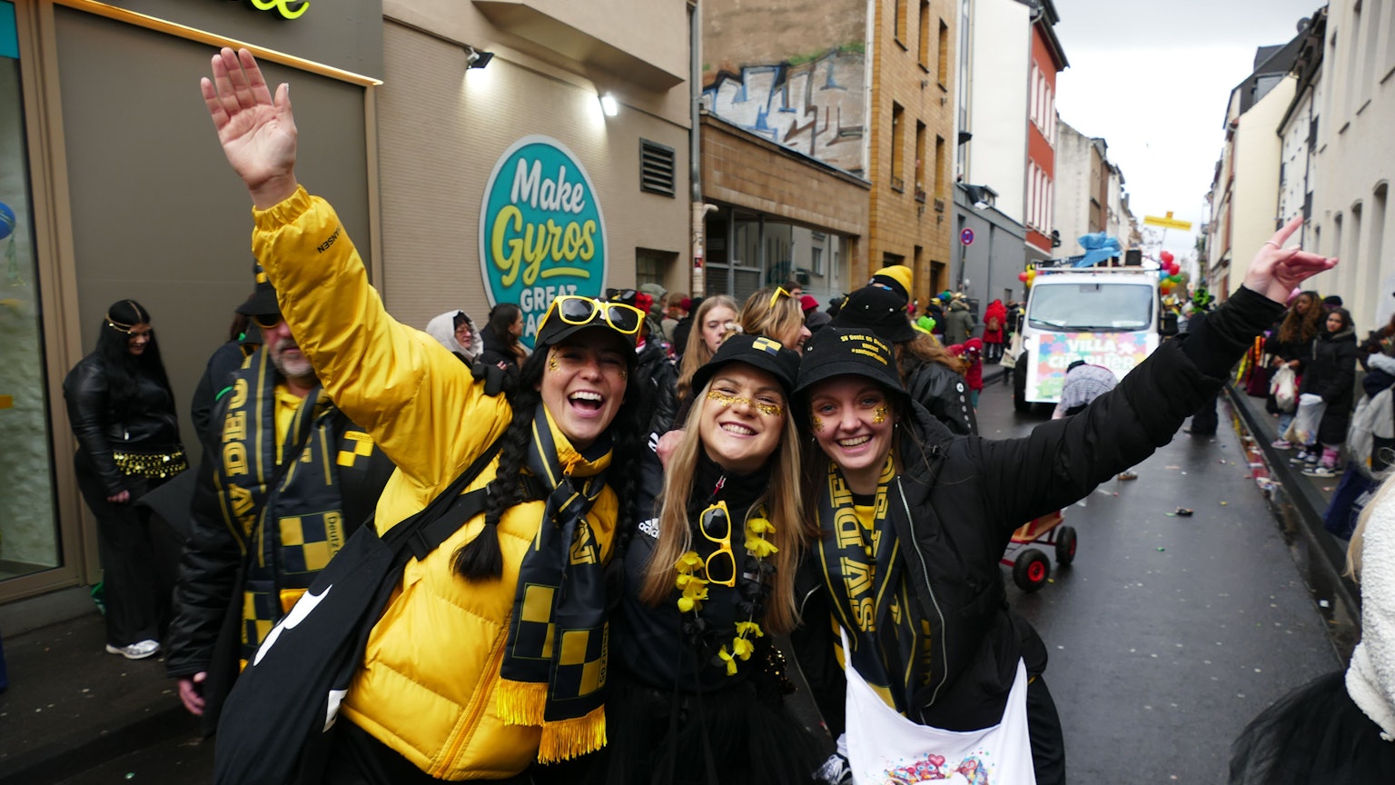 Drei Frauen in Schwarz-Gold stehen zusammen auf dem Zugweg.