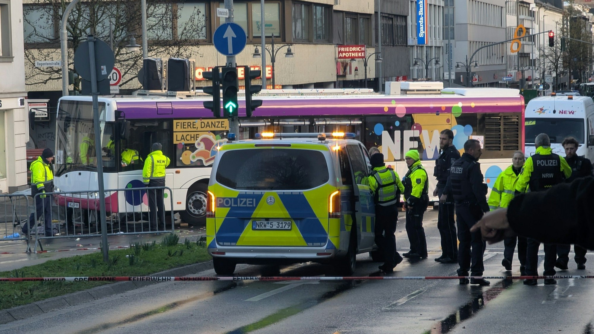 Polizisten stehen an einer Unfallstelle. Beim Karnevalsumzug in Mönchengladbach ist eine Frau unter einen Bus geraten und verletzt worden.