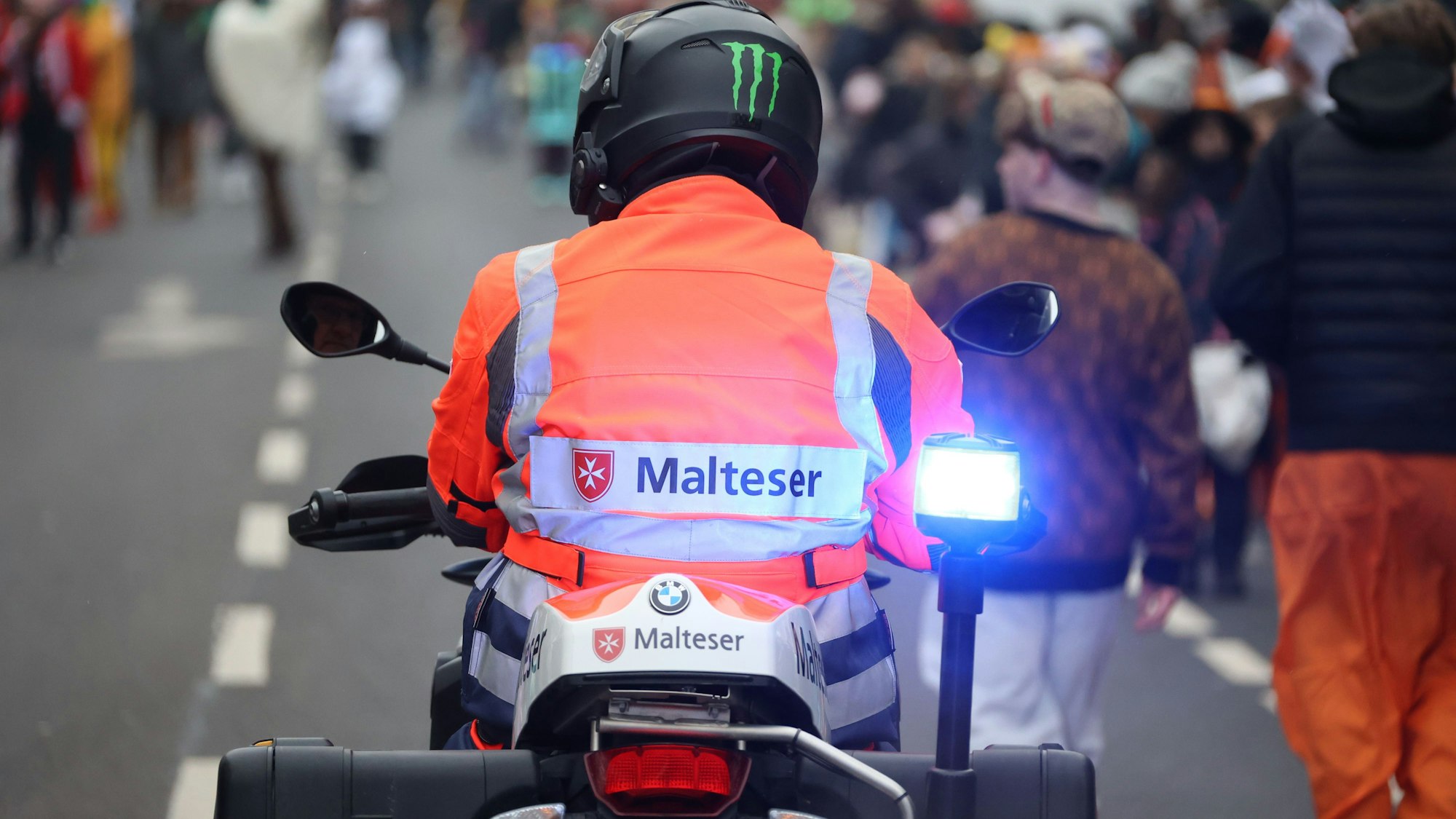 Eine Einsatzkraft des Malteser Hilfsdiensts ist auf einem Motorrad im Südstadtzug in Euskirchen im Einsatz.