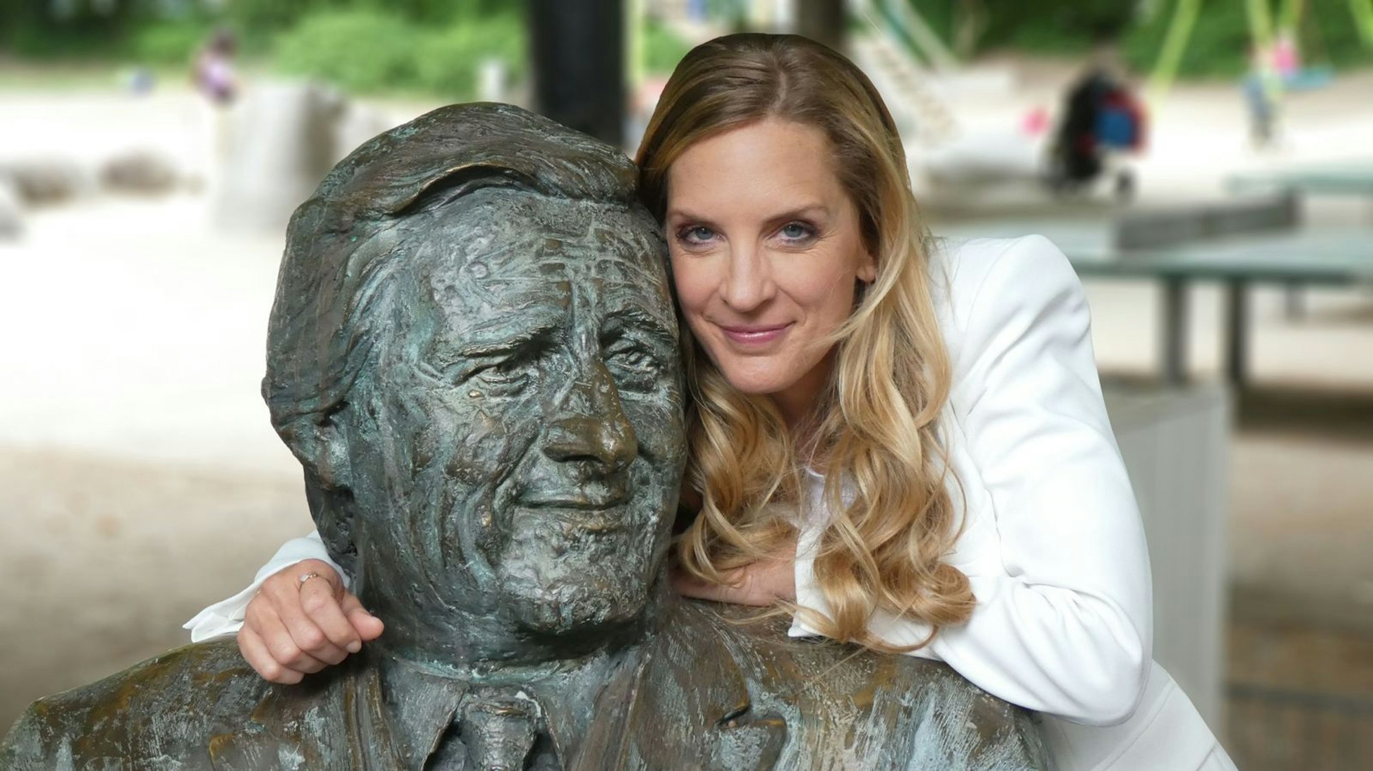 Erinnerungen an ein Original des Fernsehens und der Stadt München: Moderatorin Caro Matzko am Denkmal für Helmut Fischer als Monaco Franze vor dem Café „Münchner Freiheit“. (Bild: BR/Björn Pfeffermann)