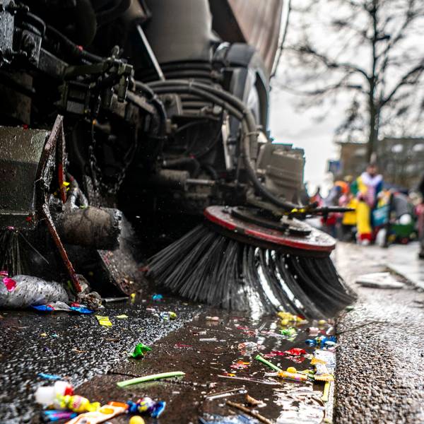 Eine Kehrmaschine sammelt die liegen gebliebenen Kamelle beim Rosenmontagszug in Euskirchen ein.