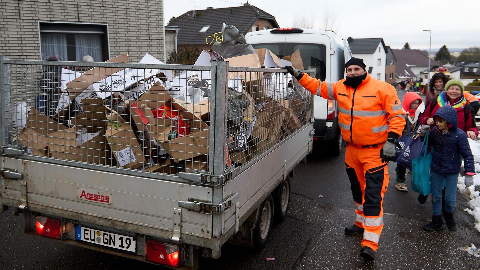 Ein Mitarbeiter des Bauhofs der Gemeinde Nettersheim steht neben einem Anhänger, in dem nach dem Karnevalszug der Müll eingesammelt wird.
