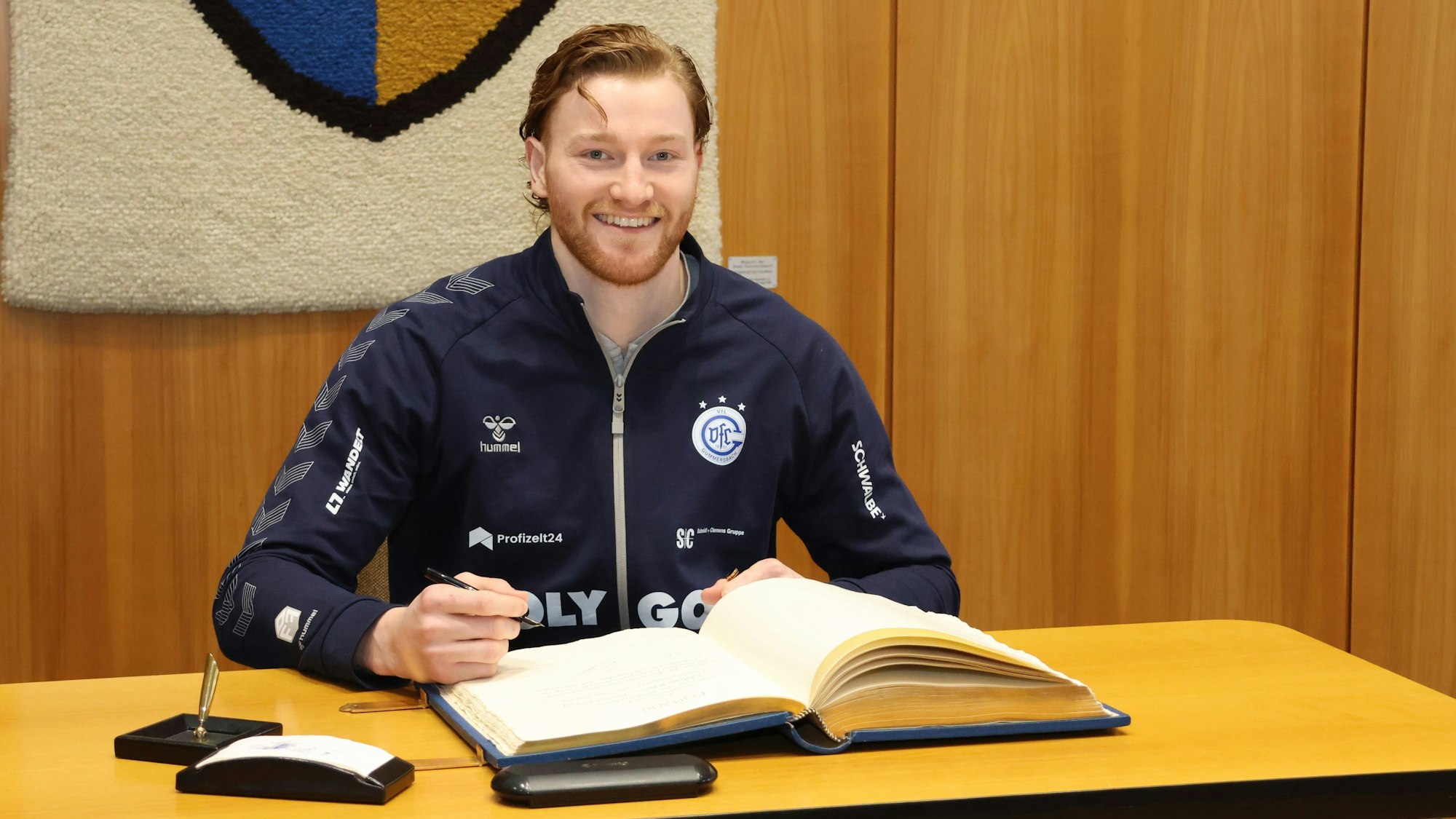 Tom Kiesler trägt sich ins Goldene Buch der Stadt Gummersbach ein.