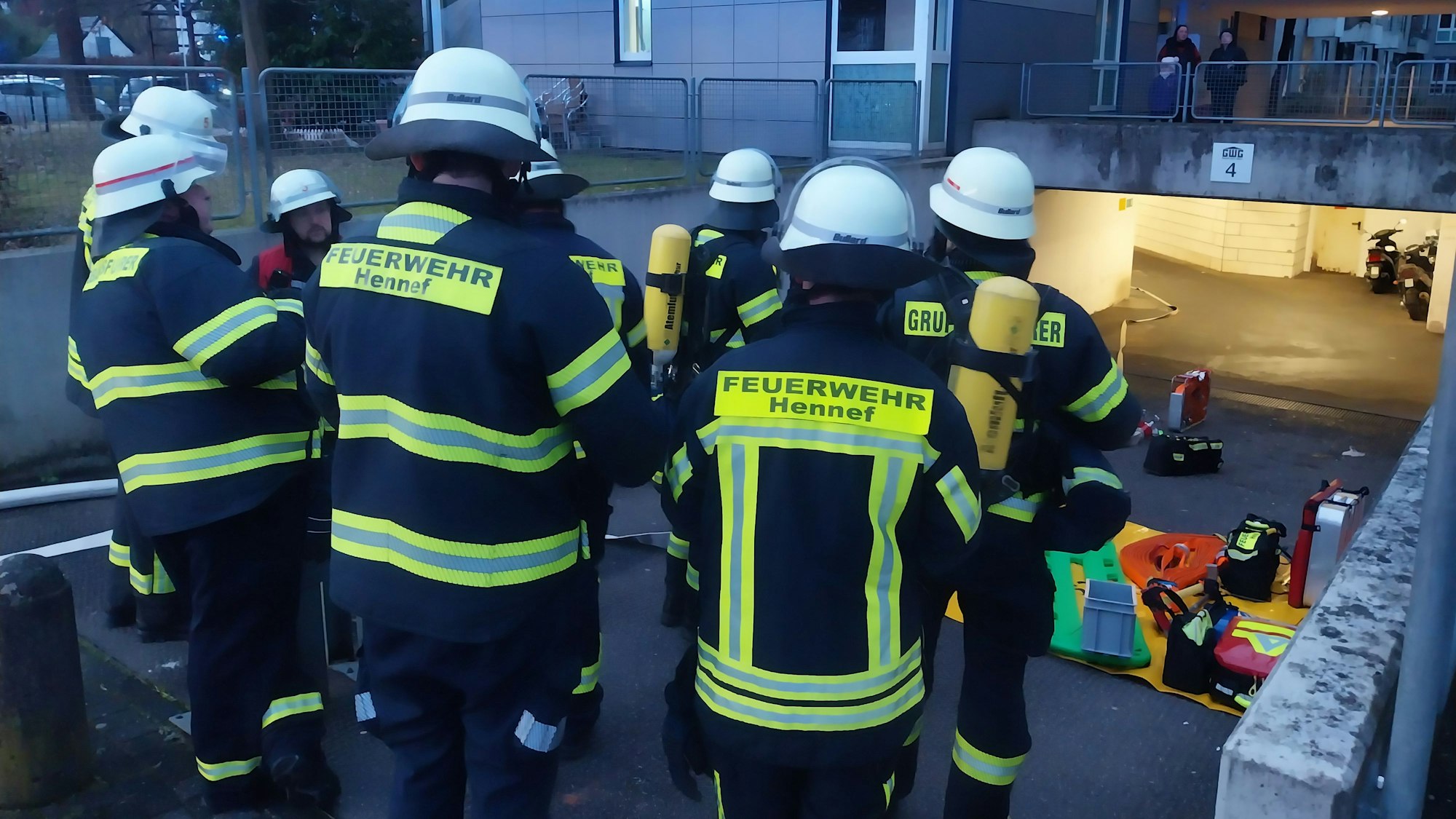 Feuerwehrleute stehen vor dem Mehrparteienhaus.