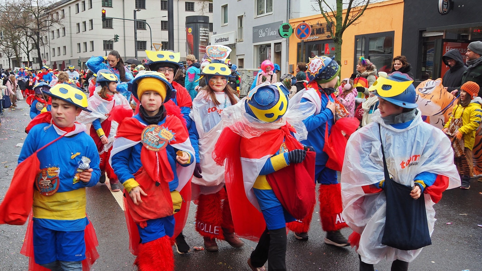 Schüler in blau-roten Kostümen laufen im Zug mit.