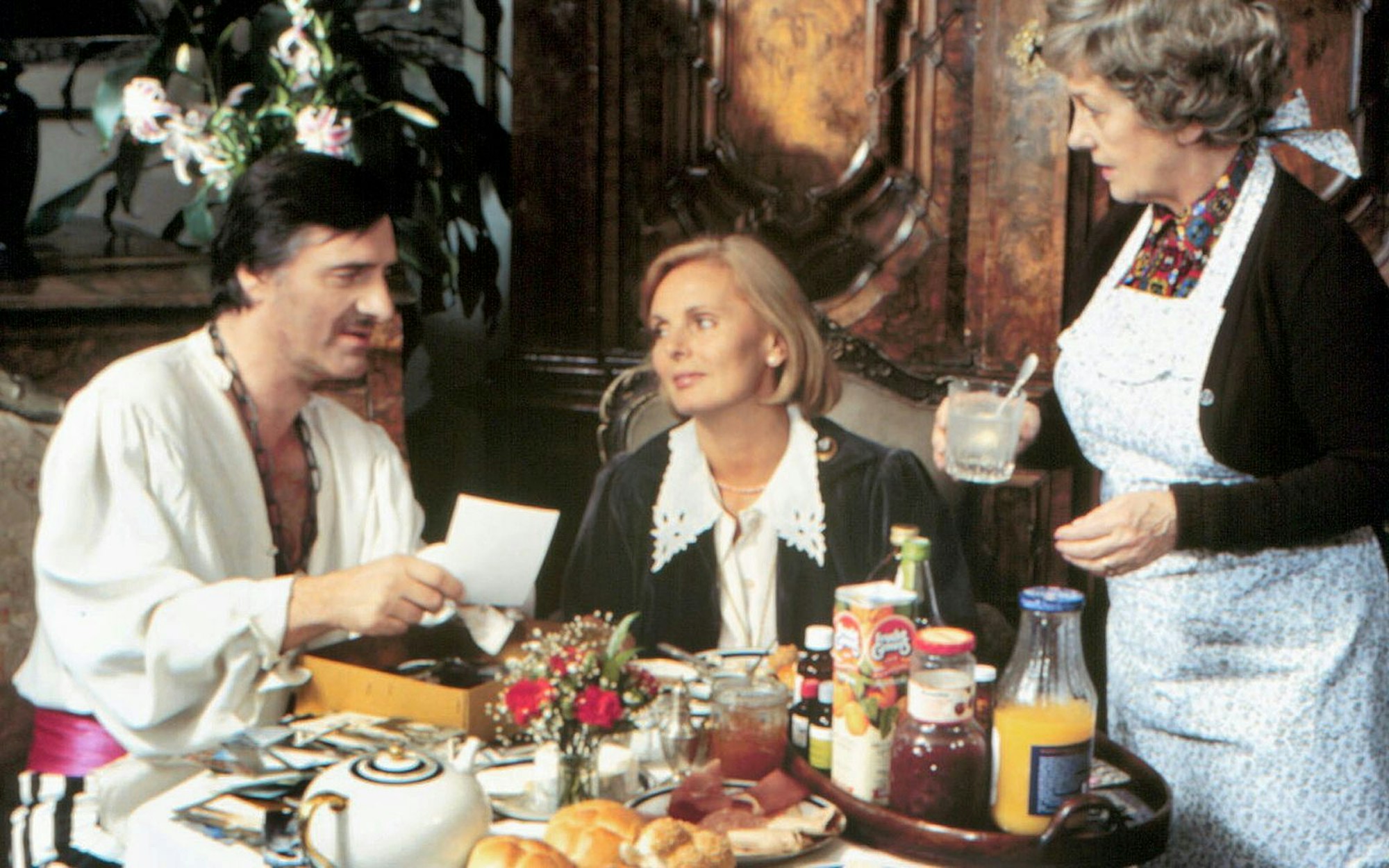 Der „Monaco Franze“ (Helmut Fischer) ist im Faschingsfieber - wenig später wird er mit echtem Fieber im Bett liegen. Ehefrau Annette (Ruth Maria Kubitschek, Mitte) und Haushälterin Irmgard (Erni Singerl) sind an seine Spinnereien längst gewöhnt. (Bild: Balance Film/BR)