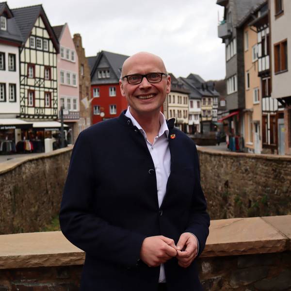 Sebastian Glatzel steht auf einer Brücke, die über die Erft führt. Im Hintergrund sieht man Bad Münstereifel.