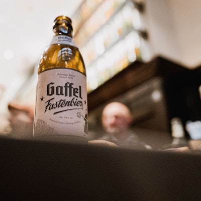 Eine Flasche Bier steht in einem Brauhaus auf einem Tisch.