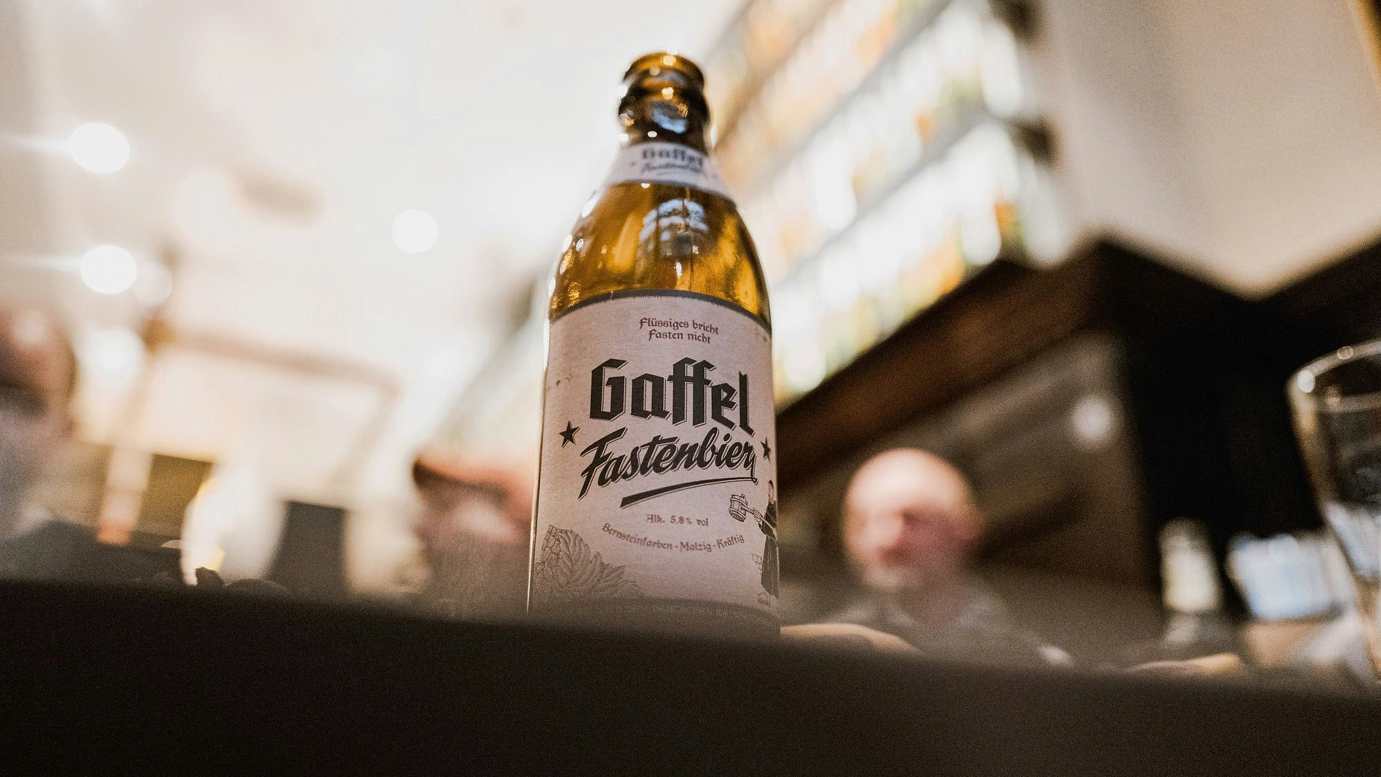 Eine Flasche Bier steht in einem Brauhaus auf einem Tisch.