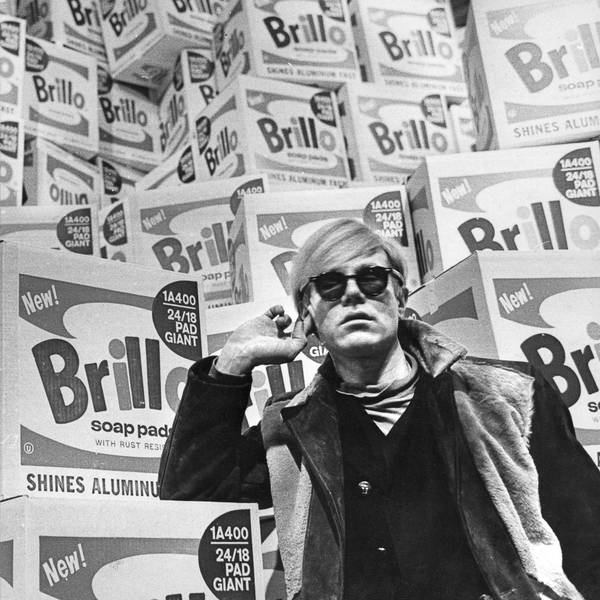 Andy Warhol lehnt an einem Stapel Verpackungen für Putzschwämme.