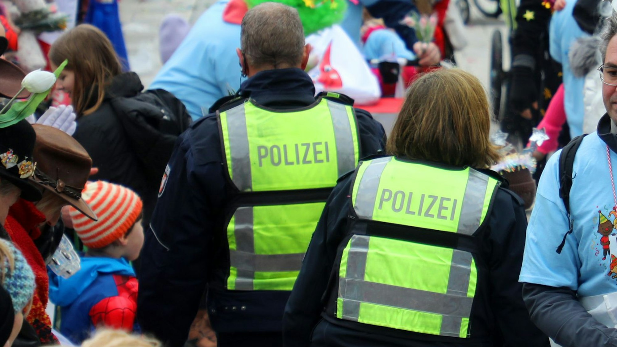 Polizeibeamte gehen durch Zuschauer des Karnevalszugs in Gladbach.