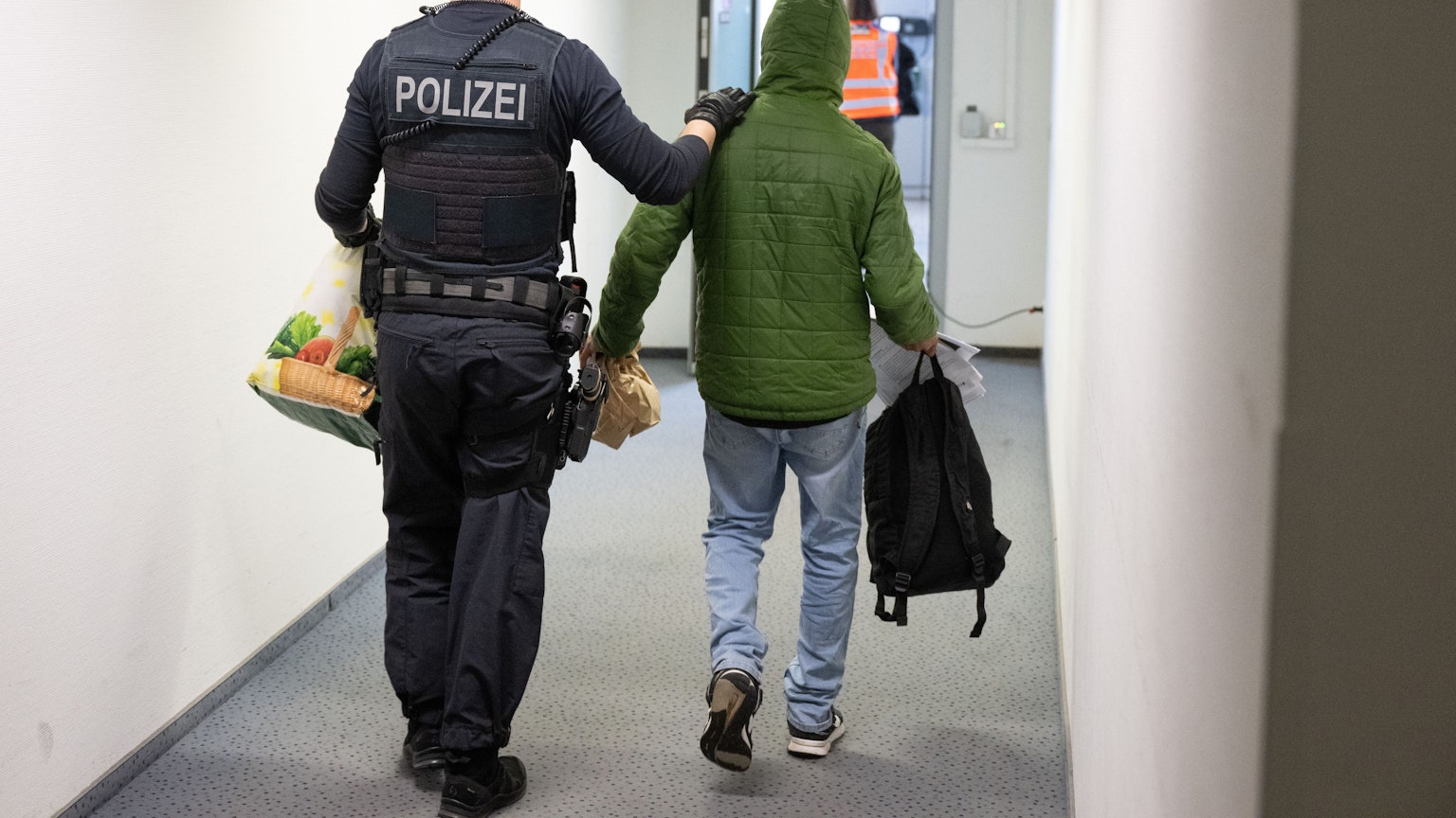 Ein Polizeibeamter bringt einen Mann zu einem Abschiebeflug nach Pakistan.