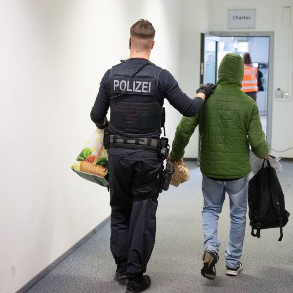Ein Polizeibeamter bringt einen Mann zu einem Abschiebeflug.