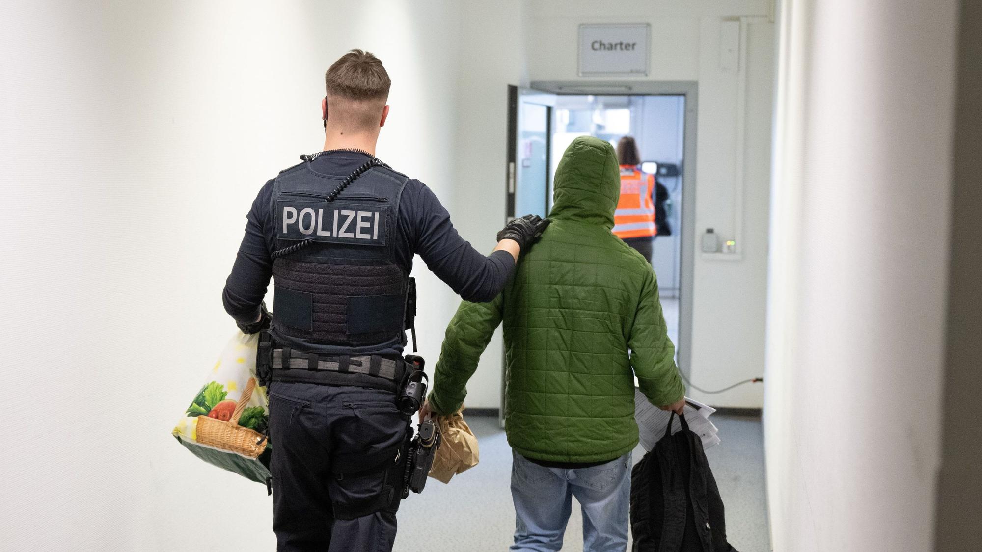 Ein Polizeibeamter bringt einen Mann zu einem Abschiebeflug.