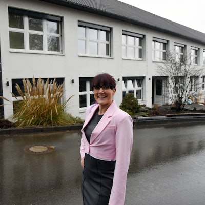 Eine Frau steht vor einem großen Gebäude, in dem demnächst ein Gesundheitszentrum eröffnet wird.