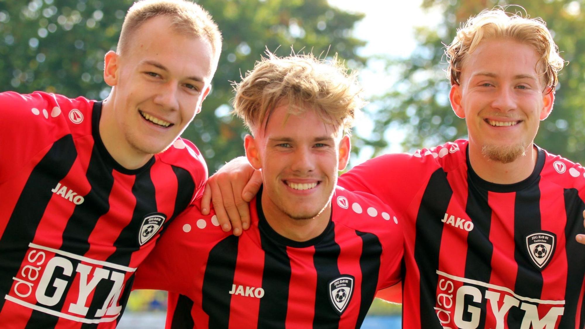 Drei Fußballer der JSG Erft 01 posieren Arm in Arm für die Kamera.