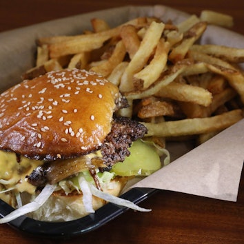 Smash Burger mit Pommes im Körbchen. (Symbolbild)
