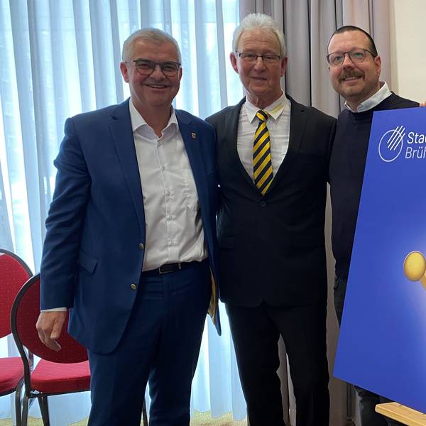 Zu sehen sind Dr. Marc Prokop, Georg Müller und Martin Lösch, sie stehen hinter einem Schild, das das Sessionsmotto zeigt.