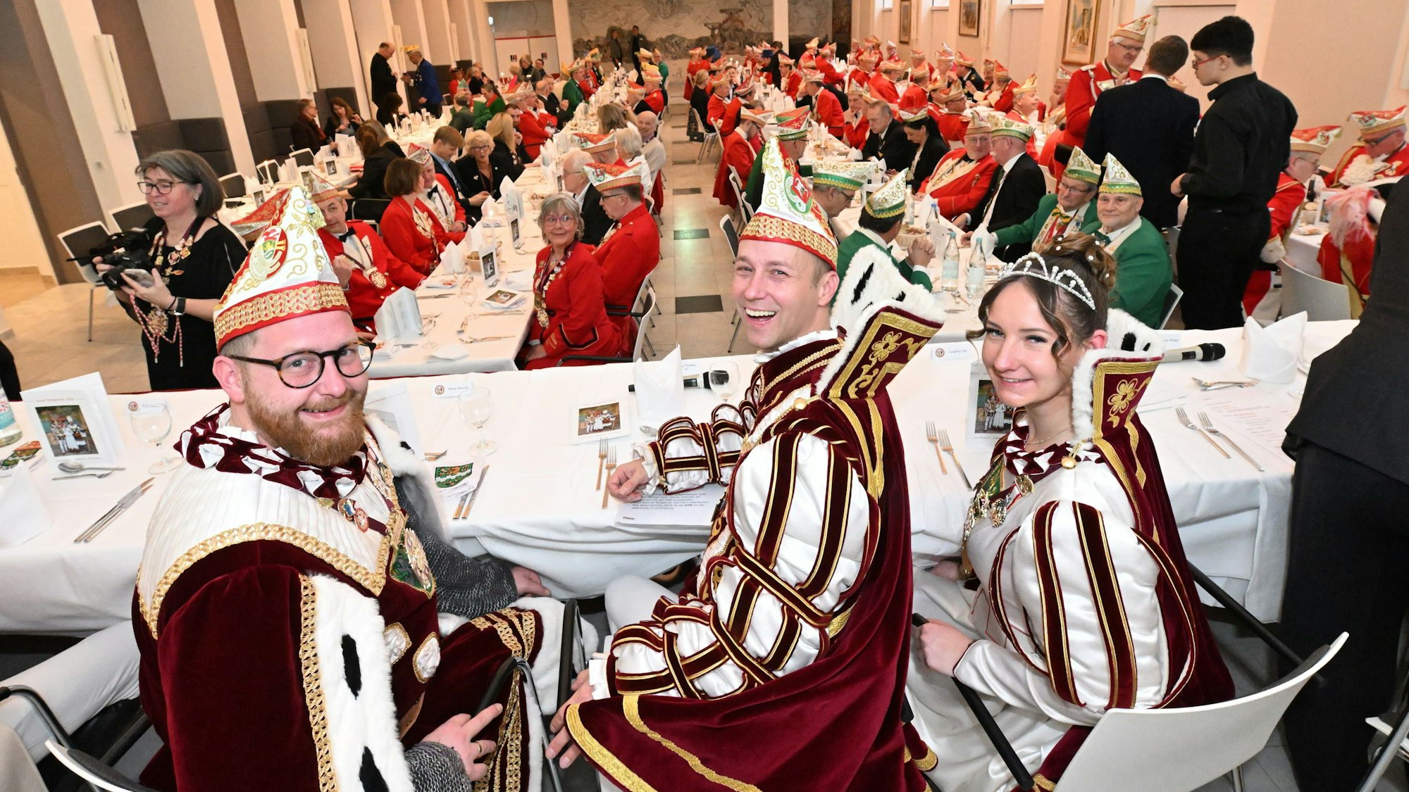 Prinz Thomas III. Bauer Maurice und Jungfrau Lea sitzen an einem Tisch beim Prinzenessen im Kardinal-Schulte-Haus.