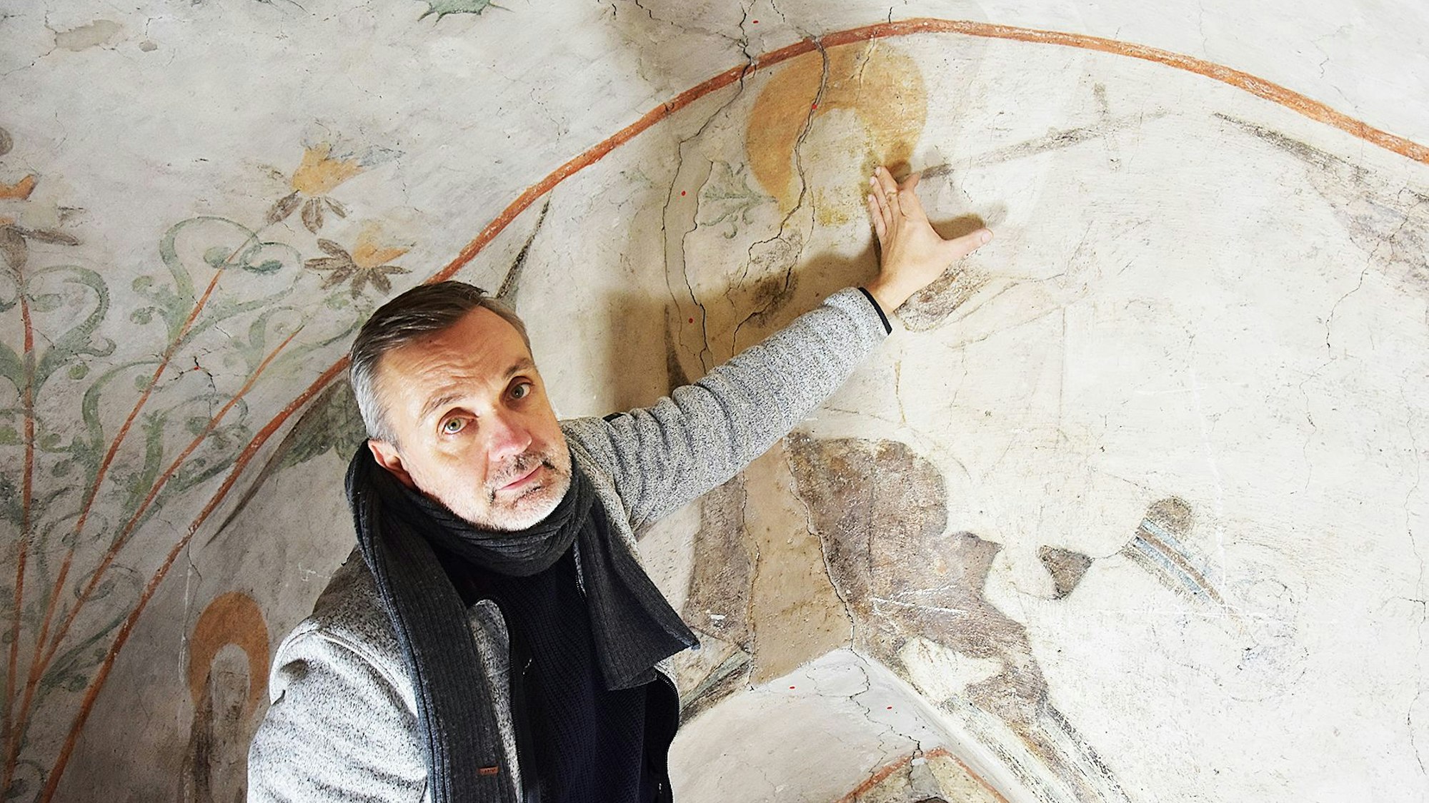 Das Foto zeigt den Restaurator Christian Rubin, der auf eine der kritischen Stellen an der Decke zeigt.