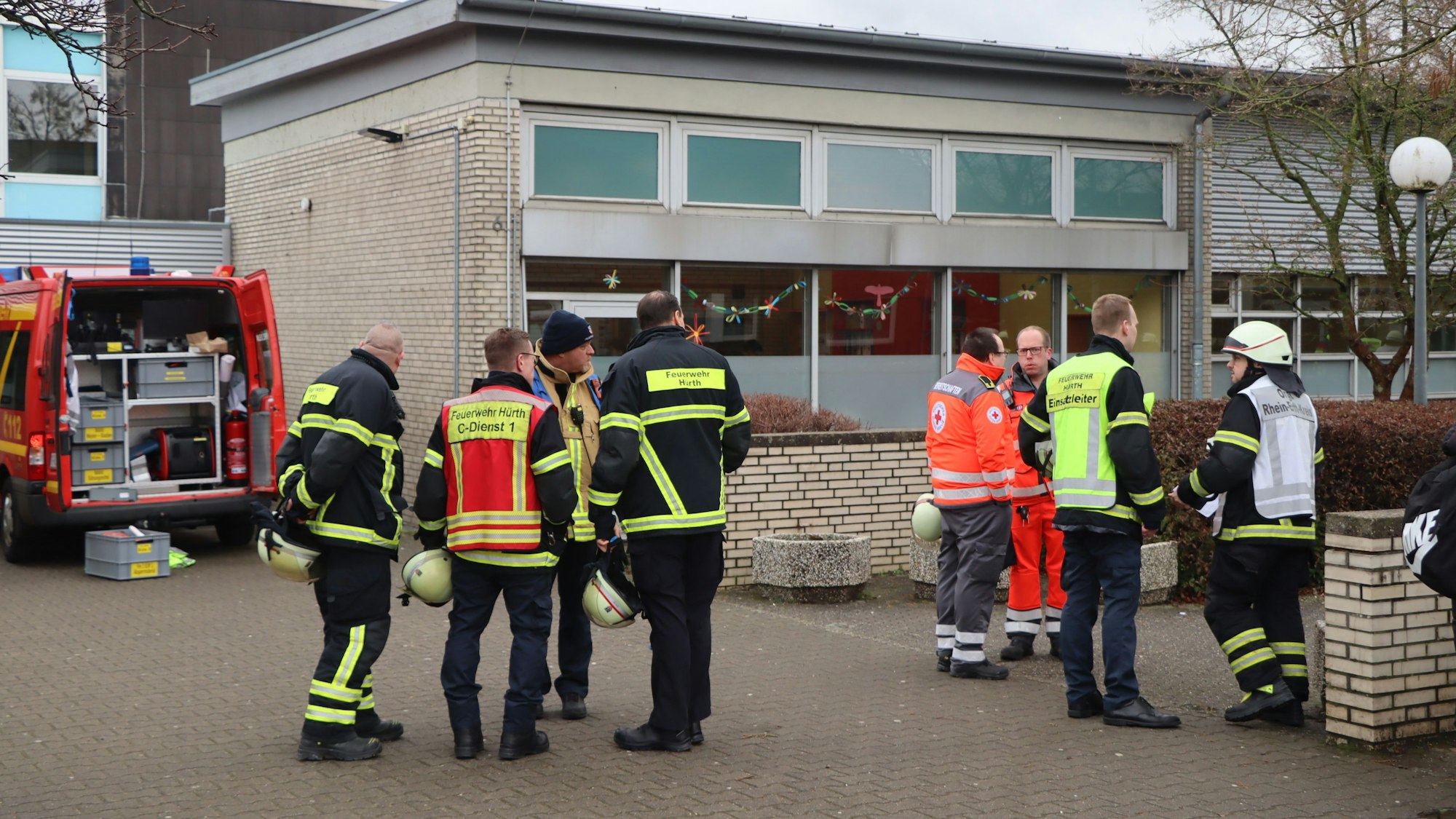 Fas Foto zeigt Einsatzkräfte und ein Einsatzfahrzeug der Feuerwehr vor dem Schulgebäude.