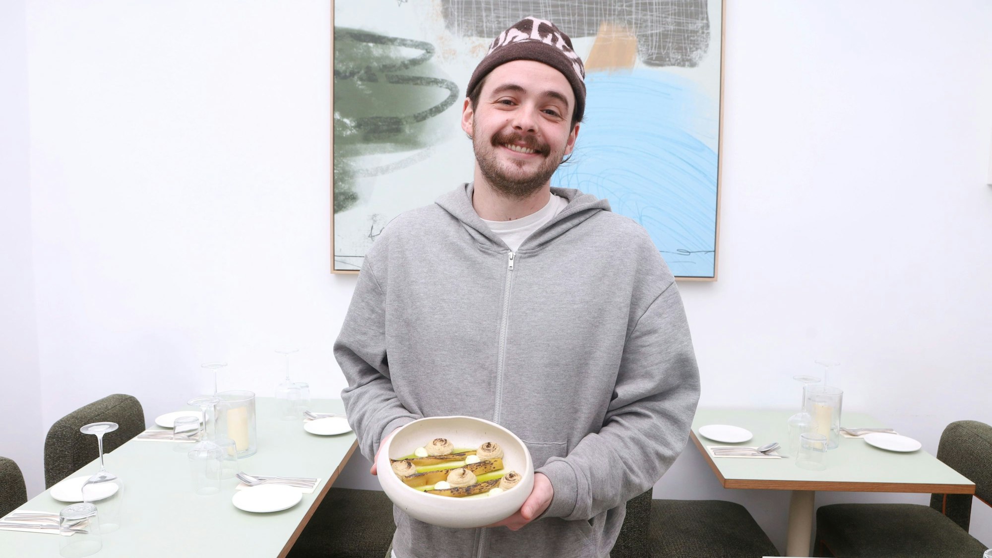18.02.2026, Köln: Gastrokolumne „Schmeckts Frau Floss?“ im ONDA. Sascha Bobb mit dem Tellergericht verbrannter Lauch Foto: Arton Krasniqi