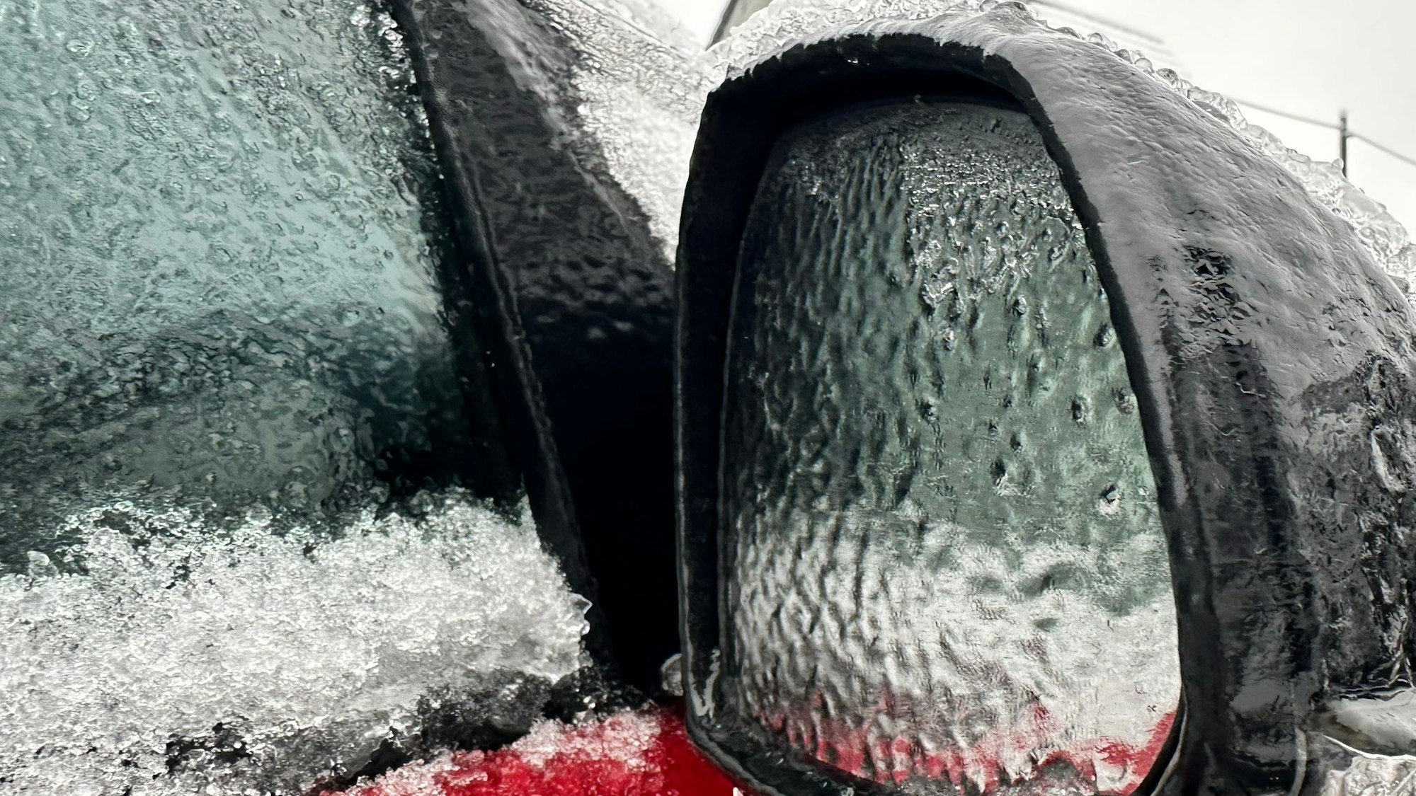 Zu sehen ist der mit Eis überzogene Außenspielgel eines Autos.