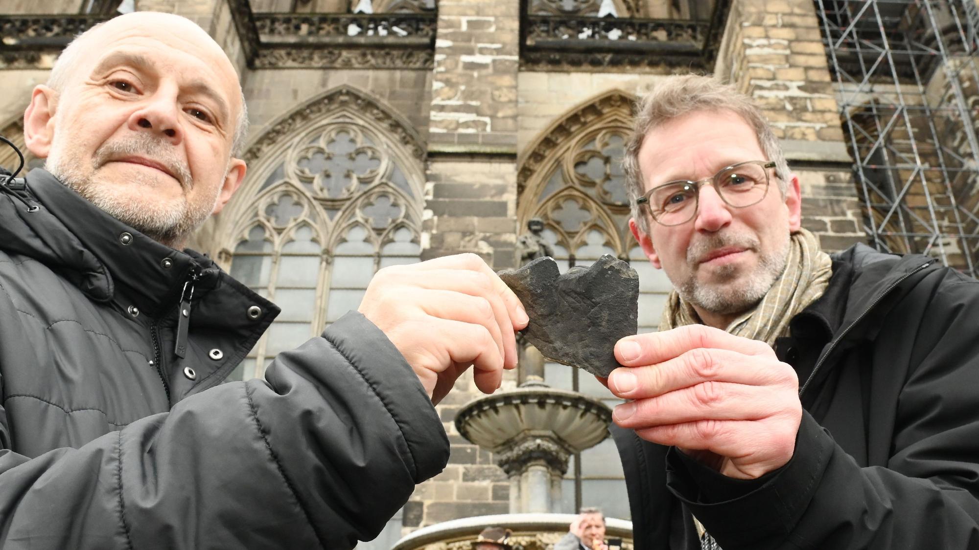 Dombaumeister Peter Füssenich (re.) übergibt eine Krabbe an Kalle Kubatschka, Vorsitzender des Kölner Alpenvereins.