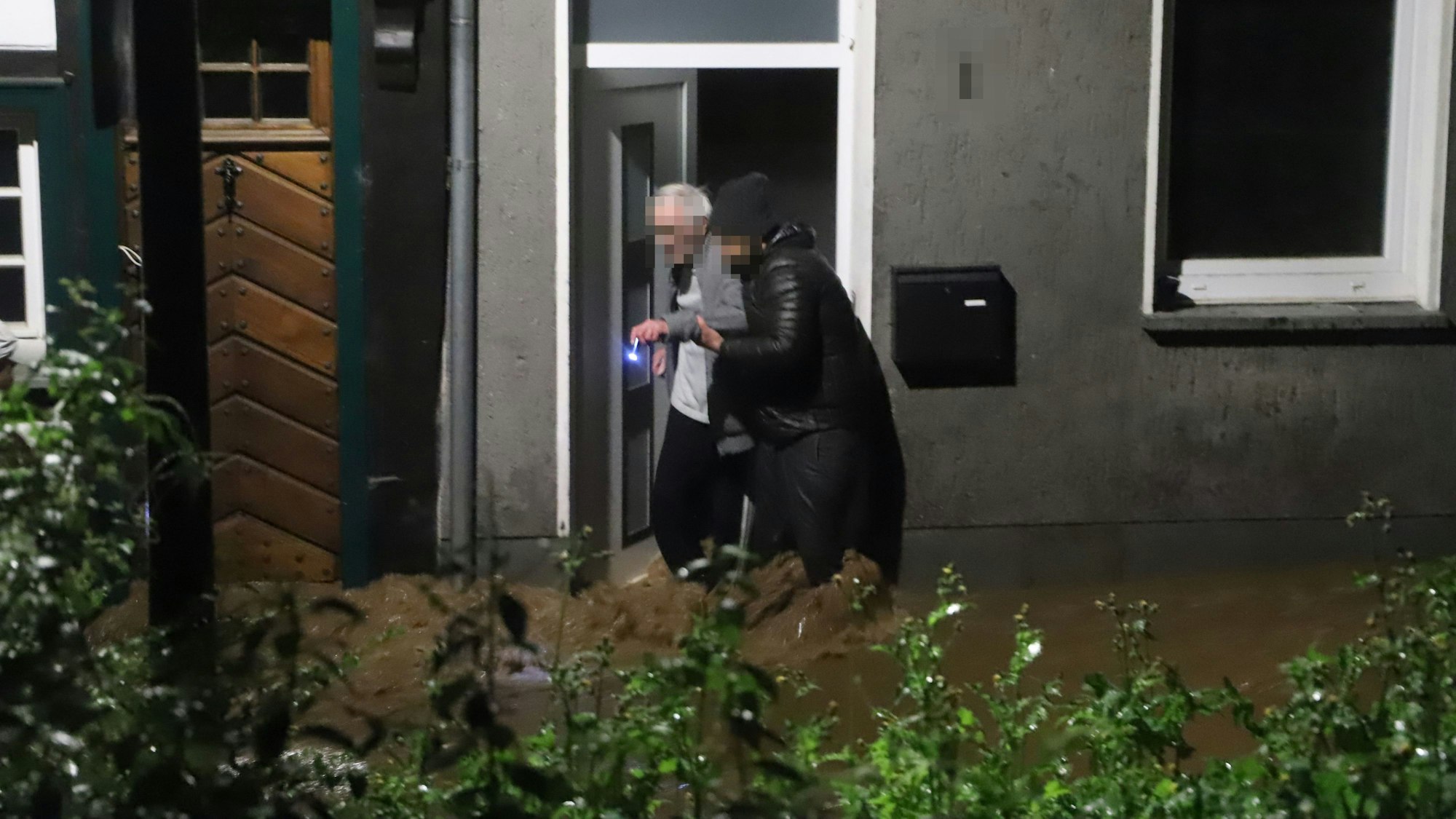 Ein junger Mann hilft einem alten Mann aus dem Haus. Aufnahme aus der Flutnacht 14./15. Juli 2021.