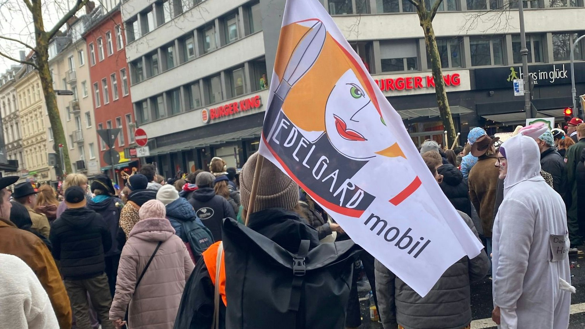Edelgard-Mitarbeiterin mit Fahne unterwegs im Straßenkarneval