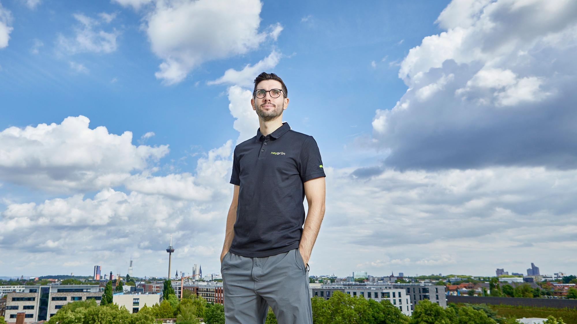 Ein Mann steht vor einer Skyline und schaut in den Himmel.