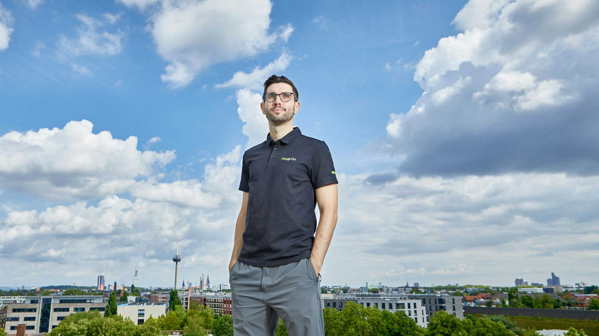 Ein Mann steht vor einer Skyline und schaut in den Himmel.