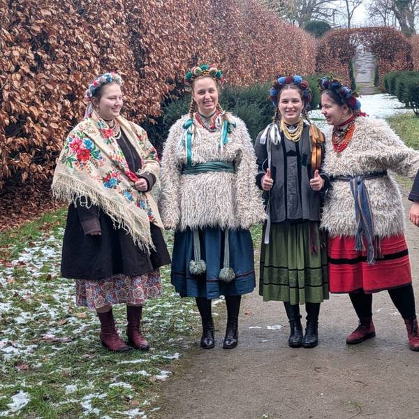 Die Frauen der ukrainischen Volksmusikgruppe Ralets stehen in traditionellen Kleidern zusammen auf einer Wiese.