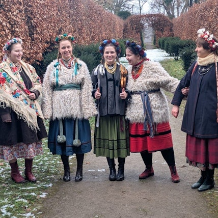 Die Frauen der ukrainischen Volksmusikgruppe Ralets stehen in traditionellen Kleidern zusammen auf einer Wiese.