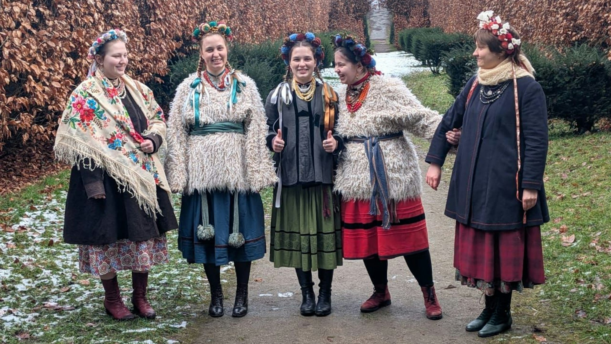 Die Frauen der ukrainischen Volksmusikgruppe Ralets stehen in traditionellen Kleidern zusammen auf einer Wiese.