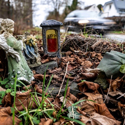 Das Bild zeigt ein Holzkreuz an einer Straße im Kreis Euskirchen. Auch eine Engelsfigur und eine Kerze stehen an der L194.