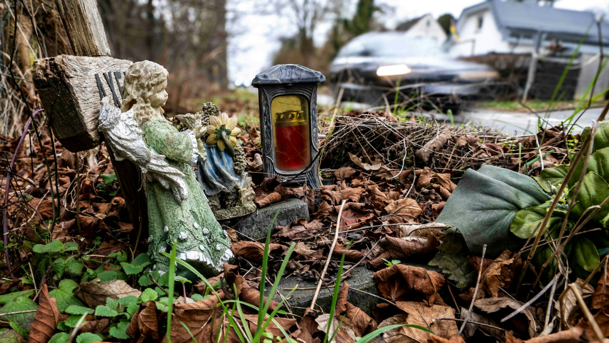 Das Bild zeigt ein Holzkreuz an einer Straße im Kreis Euskirchen. Auch eine Engelsfigur und eine Kerze stehen an der L194.