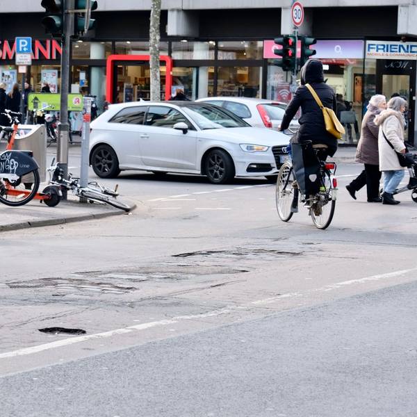 Blick auf eine Kreuzung und eine Asphaltdecke mit Löchern.