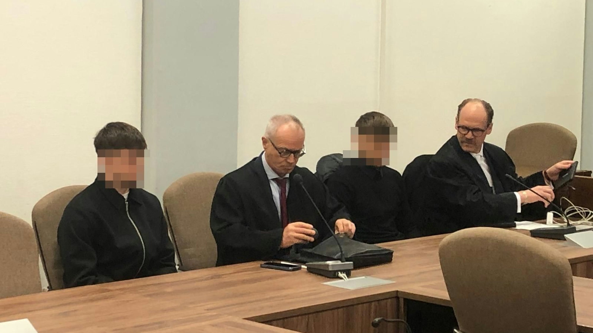 Das Foto zeigt zwei Anwälte mit ihren Anwälten, die unkenntlich gemacht wurden.