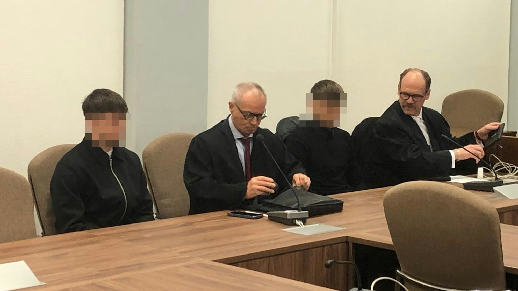 Das Bild zeigt die beiden Angeklagten mit ihren Anwälten im Gerichtssaal.