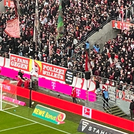 Anhänger des 1. FC Köln halten ein Spruchband gegen Polizeiwillkür hoch.
