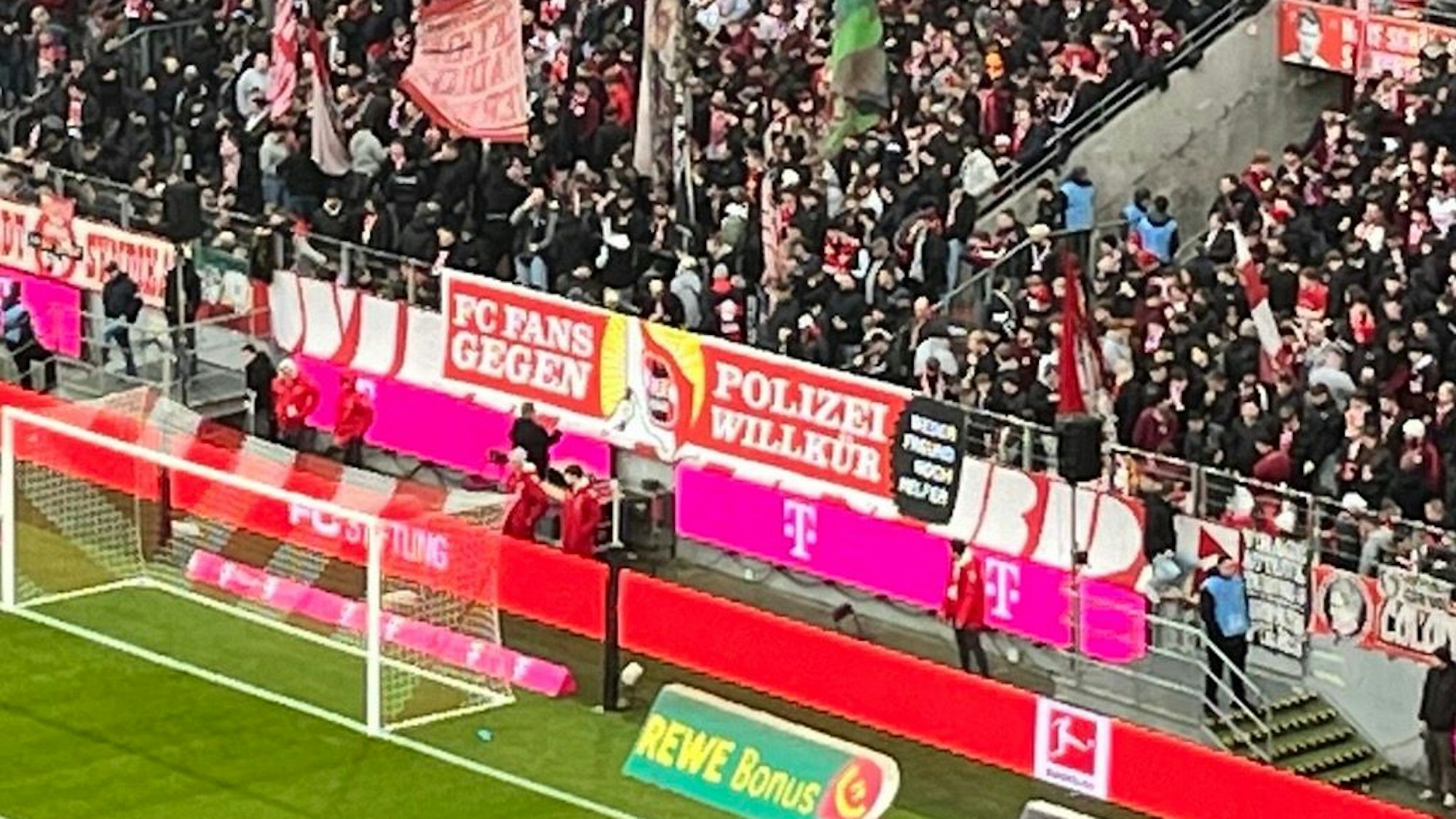 Anhänger des 1. FC Köln halten ein Spruchband gegen Polizeiwillkür hoch.
