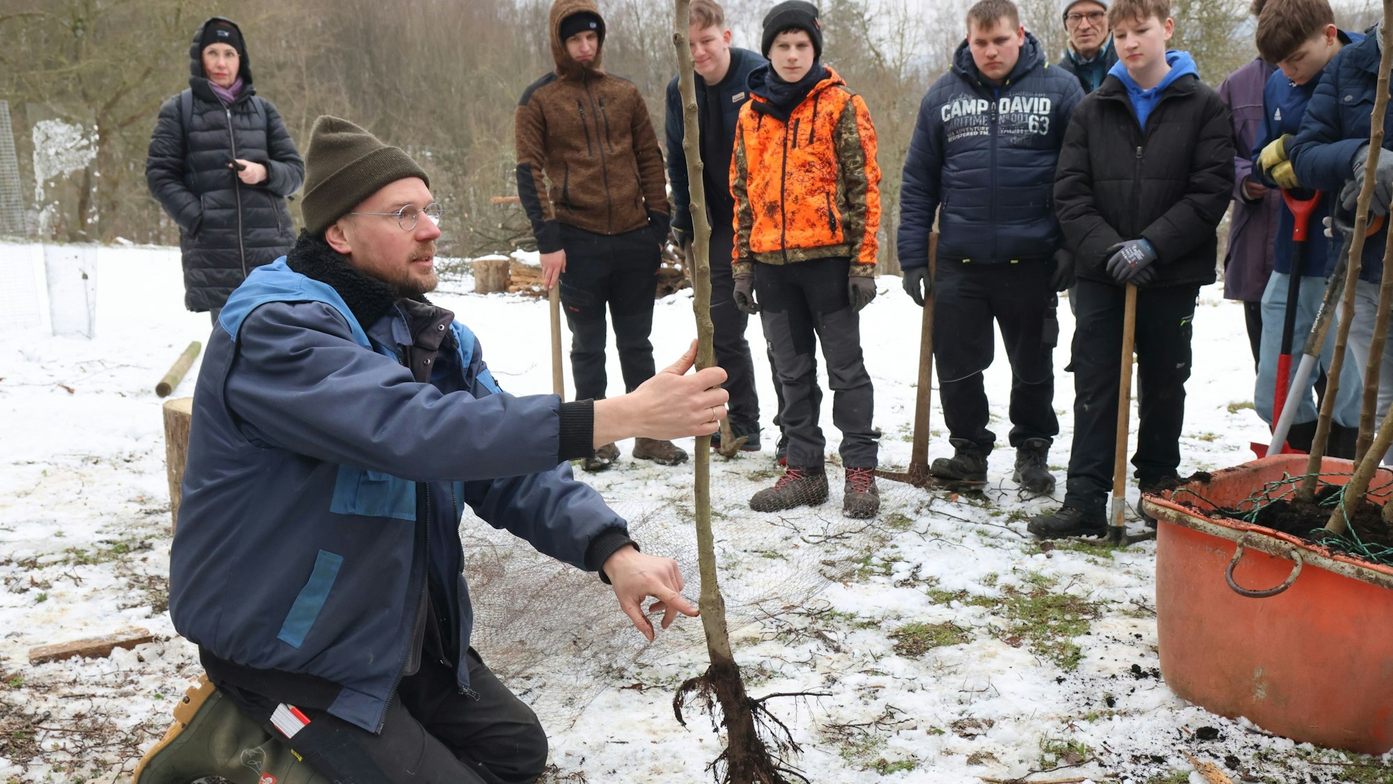 Der Engelskirchener Pädagoge Jens Herrmann gibt Tipps den Jugendlichen Tipps für das Einpflanzen der neuen Obstbäume. Diese stehen heute auf einer Wiese bei Bellingroth.