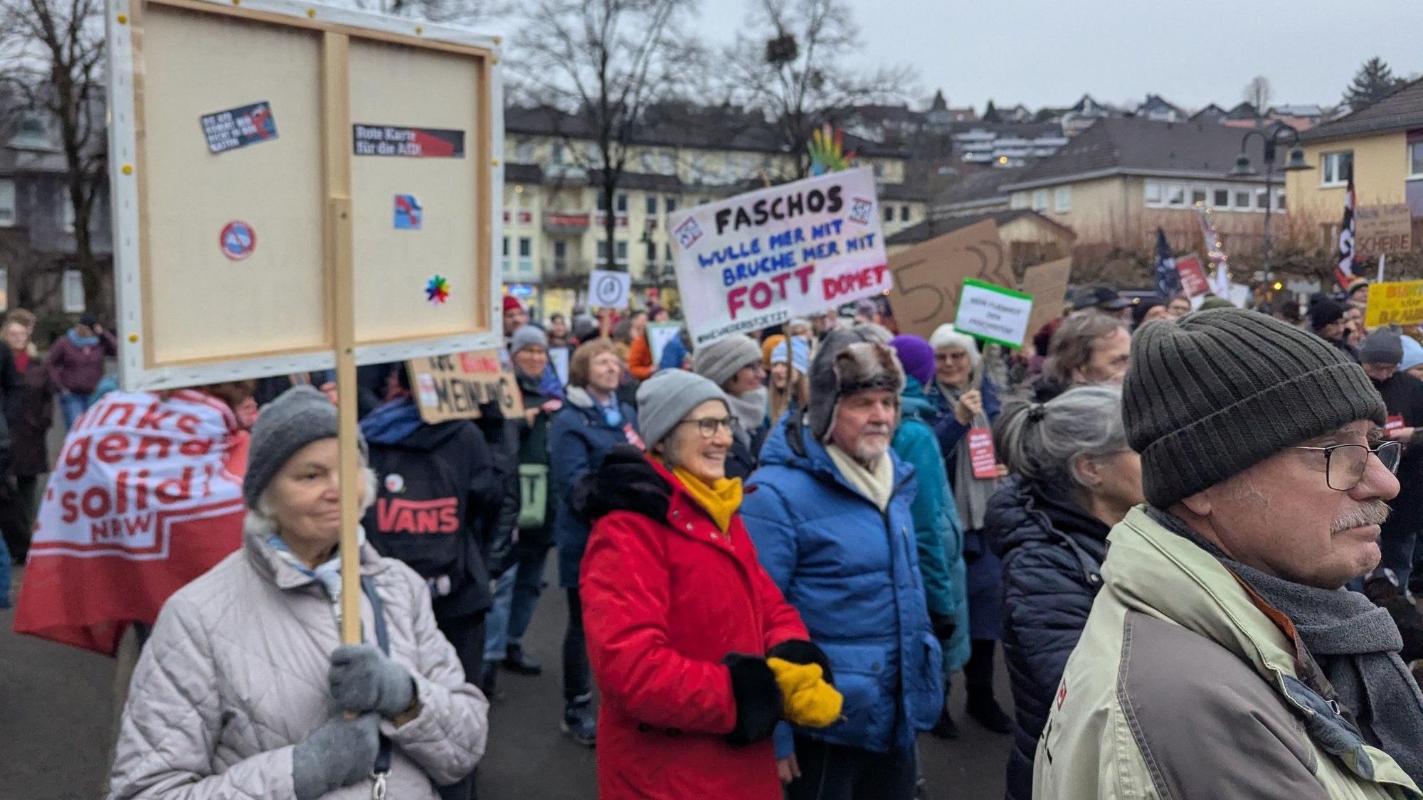 Menschen halten Protestplakate auf dem Overather Bahnhofplatz in die Höhe