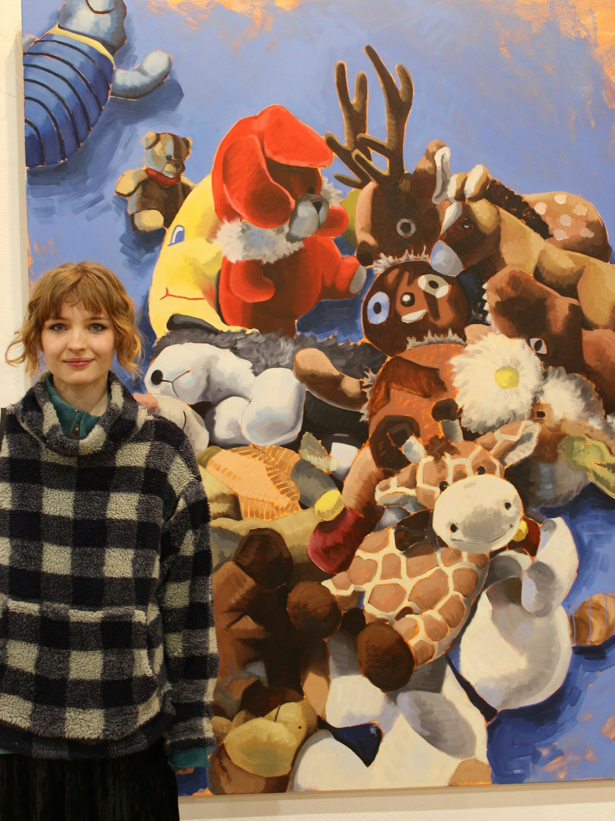 Zu sehen ist eine Künstlerin vor ihrem Gemälde.